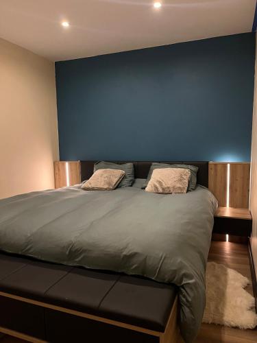 une chambre avec un lit avec un mur bleu dans l'établissement Foux d 'Allos en rez de neige, à La Foux d'Allos