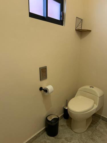 a bathroom with a white toilet and a window at Tres Iguanas Apart Hotel - New, cozy & spacious flats, short walk to beach in Loreto