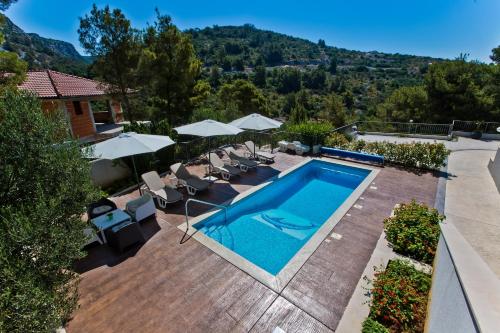 a swimming pool with chairs and umbrellas on a house at ISLAND HVAR LUXE Holiday Villa Maslina with Beach in Milna