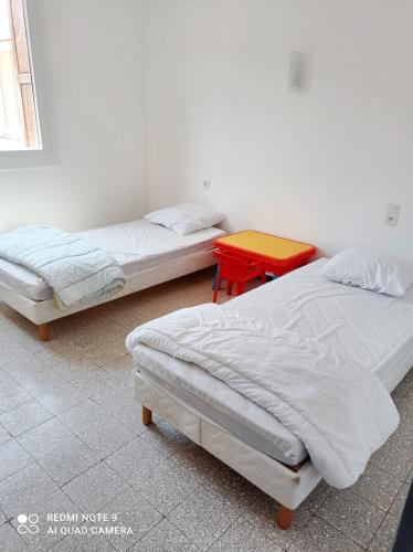 - 2 lits dans une chambre avec une table rouge dans l'établissement Appartement charmant à Ria-Sirach avec vue sur montagnes, 80 m², à Ria