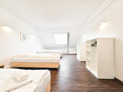 two beds in a room with white walls and wooden floors at Tolstov Apartments - City Center Apartments with 5 Rooms - 10 Min Messe DUS in Düsseldorf