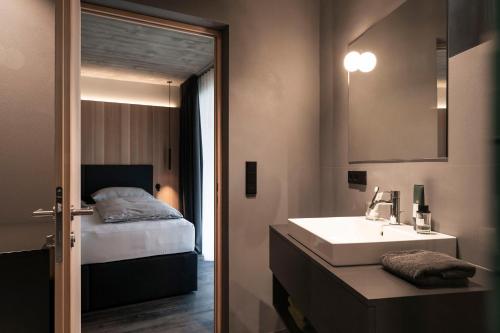 a bathroom with a bed and a sink and a mirror at apartments arduus - high living in Naturno