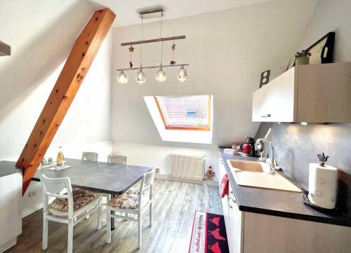 une cuisine avec un évier et une table avec des chaises dans l'établissement Le papillon,Logement cosy en Alsace, à Erstein
