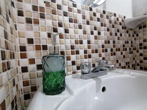 a green glass bottle sitting on a bathroom sink at Magnolia Andina in Cusco