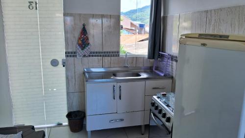 a small kitchen with a sink and a stove at Residencial Caiobá II in Matinhos