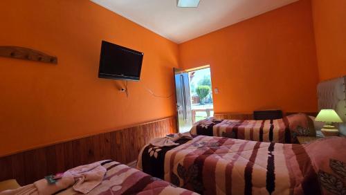 a bedroom with two beds and a tv on the wall at El Viejo in Río Mayo