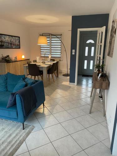 un salon avec un canapé bleu et une table dans l'établissement Blue Cottage - Charme & Verdure, à Saint-Martin-lez-Tatinghem