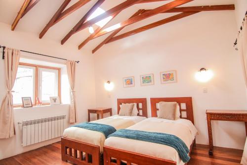 two beds in a bedroom with wooden ceilings at QOSQO BELVEDERE, apartamento en Cuesta San Blas in Cusco