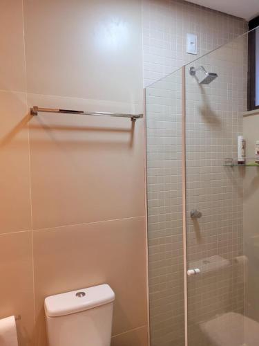a bathroom with a toilet and a glass shower at Loft Charmoso com Rooftop no Vila das Dunas in Flecheiras