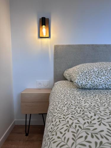 - une chambre avec un lit et une table de chevet avec un oreiller dans l'établissement La Maison N6, à Saint-Joseph