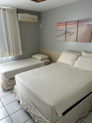 two beds in a room with white walls at Gran Lençóis Flat Residence Apartamento Caburé 610 in Barreirinhas
