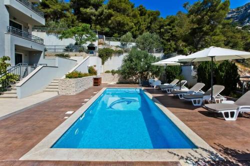 a pool with chairs and umbrellas next to a house at ISLAND HVAR LUXE Holiday Villa Maslina with Beach in Milna