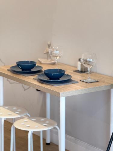 a table with two bowls and wine glasses on it at Luxury Super-King Bed Flat in Town Centre in Northampton