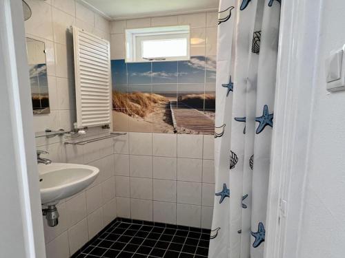 a bathroom with a sink and a shower curtain at Pet-friendly bungalow near Beach in Sint Maartenszee