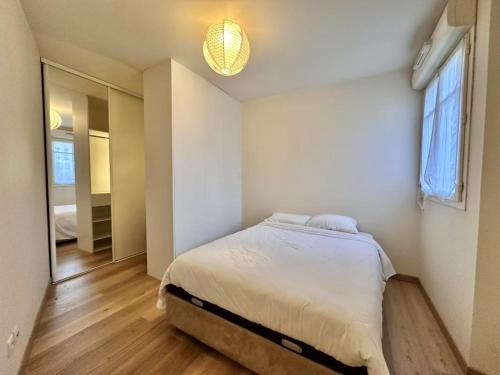 une chambre blanche avec un lit et une fenêtre dans l'établissement Appartement calm au maison des arts de Plessis, au Plessis-Robinson