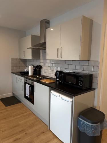 a kitchen with white cabinets and a black microwave at Luxury Super-King Bed Flat in Town Centre in Northampton