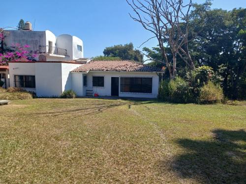 a white house with a large yard in front of it at Casa con alberca y jardin en parres jiutepex in Jiutepec