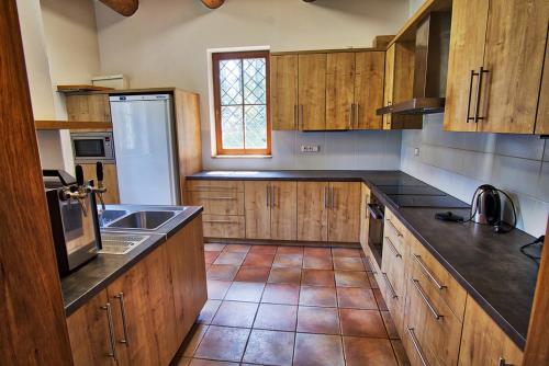 a kitchen with wooden cabinets and a tile floor at Chata BABÍ LOM in Lelekovice