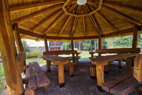 a wooden gazebo with wooden benches and tables at Chata BABÍ LOM in Lelekovice