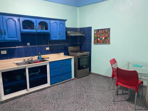 a kitchen with blue cabinets and a sink and a red chair at Casa Azul - Apartment in San Felipe de Puerto Plata