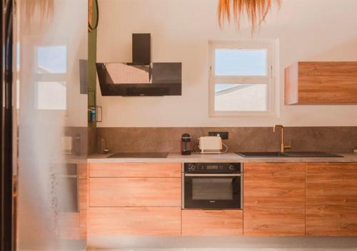 une cuisine avec des armoires en bois et un four à plaques de cuisson dans l'établissement Duplex moderne à 5 min Aix, à Aix-en-Provence