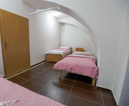 two beds with pink sheets in a room with an arch at Hostel - Rooms Kaj & Kaja in Slivnica pri Mariboru