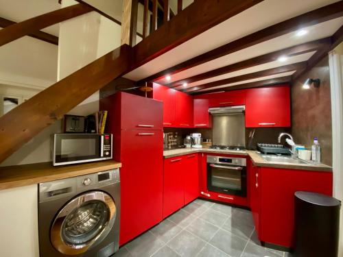 - une cuisine avec des placards rouges et un lave-linge dans l'établissement Appartement Vue sur Seine, à Paris