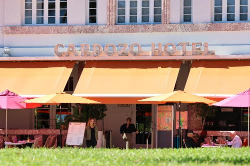 a group of people standing outside of a building with umbrellas at Cardozo Hotel in Miami Beach