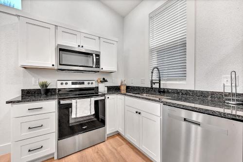 a kitchen with white cabinets and stainless steel appliances at Decca's Uptown Oasis in Siloam Springs