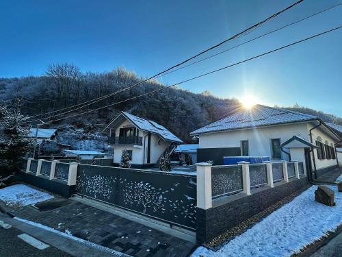 a house with a fence in the snow at Vila Casa Din Vale - Valiug in Văliug