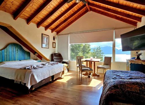 une chambre avec un lit et une table et une grande fenêtre dans l'établissement Puerto Esmeralda ESPECTACULAR DEPTO CON VISTA AL LAGO NAHUEL HUAPI, à Villa La Angostura