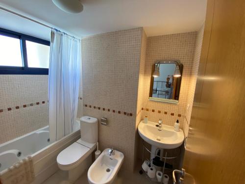 a bathroom with a white toilet and a sink at Apartamento Port Dénia in Denia
