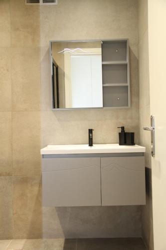 a bathroom with a white sink and a mirror at Pirgos Cozy Apartment for 4 by MPS in Pýrgos