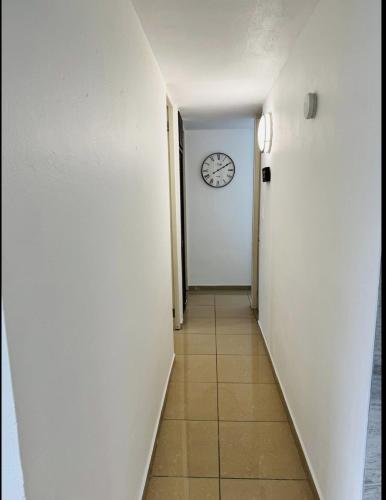 a hallway with a clock on a white wall at Hollywood Apartments - H in Yabucoa