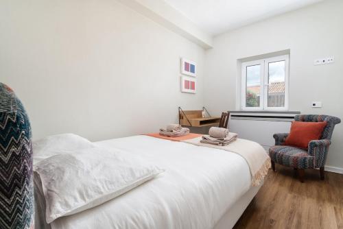a white bedroom with a bed and two chairs at Casa Arte 5 in Aljezur