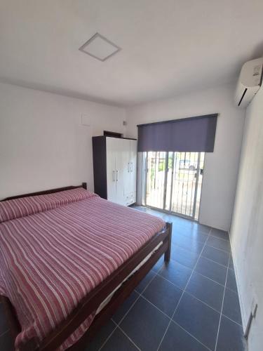 ein Schlafzimmer mit einem Bett und einem großen Fenster in der Unterkunft Habitación con Baño Privado in Maldonado