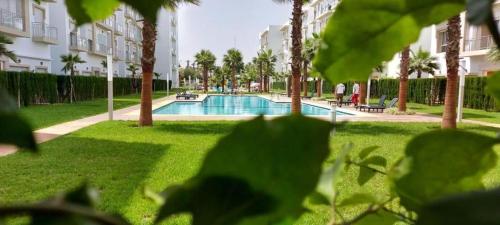 a swimming pool in a park with palm trees at Résidence kettani piscine bouznika in Bouznika