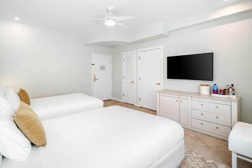 a white bedroom with two beds and a flat screen tv at Cardozo Hotel in Miami Beach