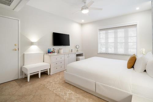 a white bedroom with a white bed and a tv at Cardozo Hotel in Miami Beach