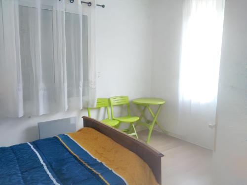 a bedroom with a bed and two green stools at Appartement agréable à Jonzac de 35 m² avec parking privé in Jonzac