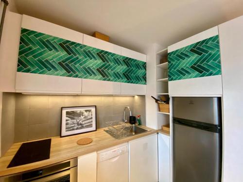 une cuisine avec des armoires blanches et un réfrigérateur en acier inoxydable dans l'établissement Appartement Censier Monge, à Paris