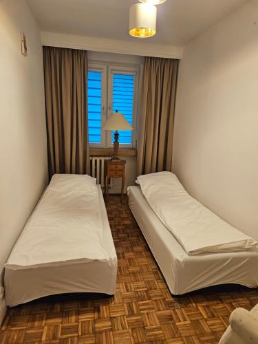 two beds in a small room with a window at Apartament Milanówek in Milanówek