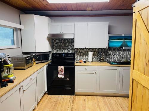 a kitchen with white cabinets and a black stove at Bastrop Tiny Disc Golf Retreat in Bastrop
