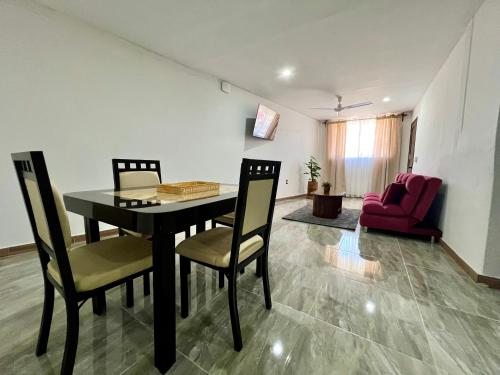 a dining room with a table and chairs and a red couch at Huitzilin Hostal in Brisas de Zicatela