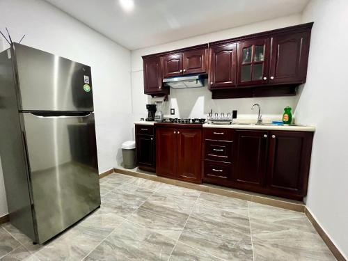 a kitchen with wooden cabinets and a stainless steel refrigerator at Huitzilin Hostal in Brisas de Zicatela