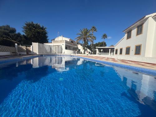 Una gran piscina azul al lado de un edificio en Can Alfredo, Apartamento Cala en Bosch con piscina, terraza y jardín privado, en Cala'n Bosch
