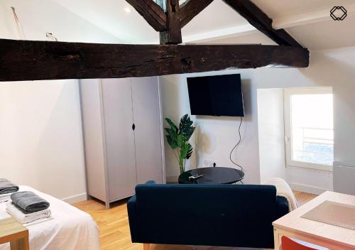 un salon avec un canapé et une télévision au mur dans l'établissement Studio Nid Urbain, à Angoulême