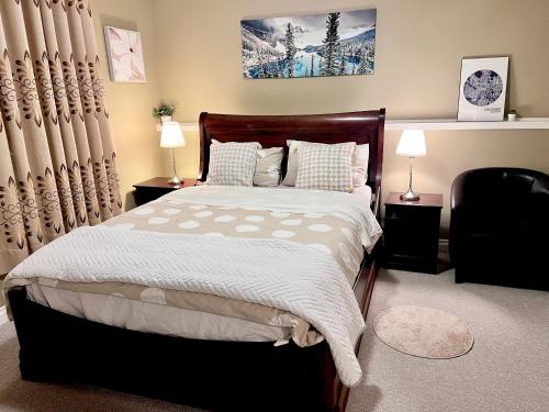 1 dormitorio con 1 cama, 2 lámparas y 1 silla en Cozy Walkout suite with King bed, Kitchen, Parking & Patio, en Calgary