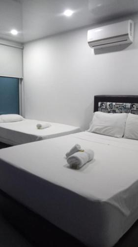 ein weißes Schlafzimmer mit 2 Betten und einer Lampe in der Unterkunft Okawango Hotel in Girardot