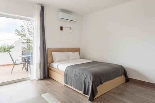 a white bedroom with a bed and a balcony at Estúdio 21 em Santa Bárbara de Nexe - Faro in Santa Bárbara de Nexe